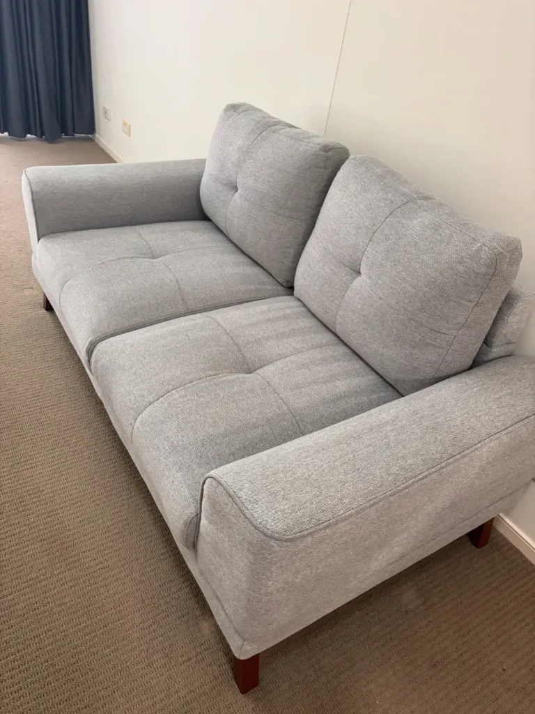 The same couch after cleaning with a lighter, more even fabric appearance.