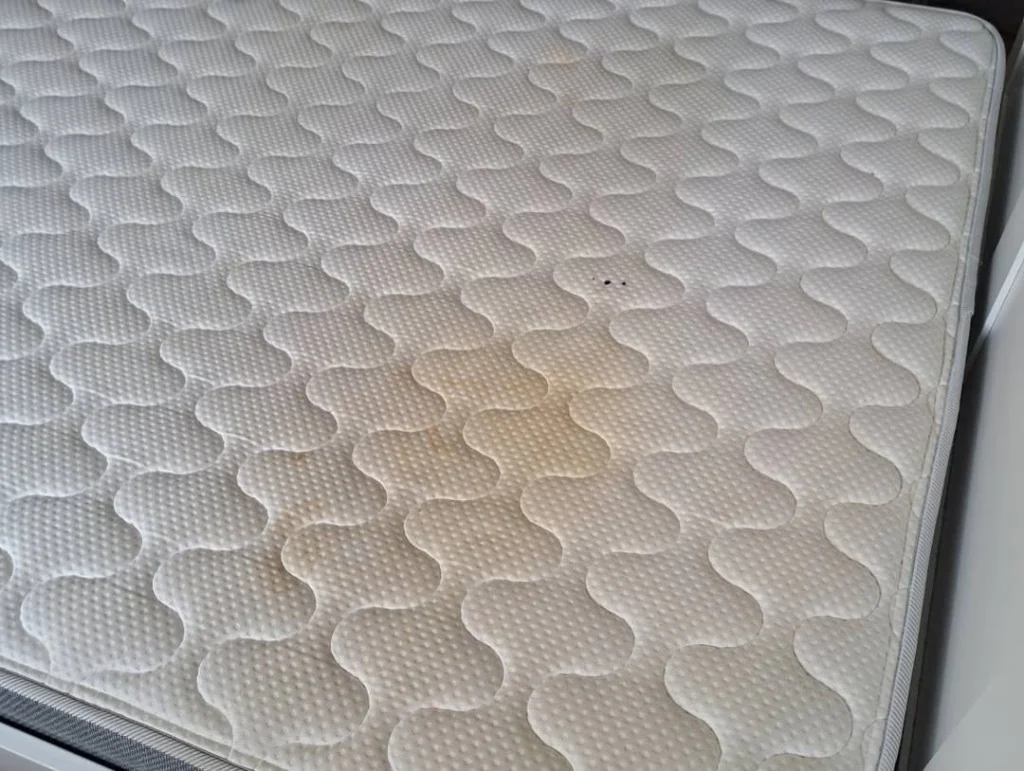 Mattress top with visible staining before professional cleaning.